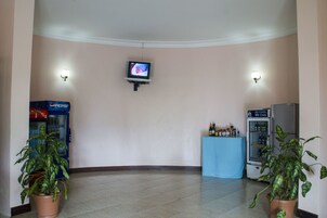 A lobby with a television mounted on the wall, vending machines, and potted plants.