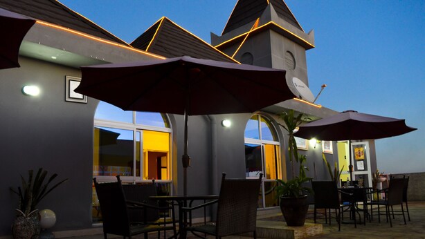 An outdoor patio area with tables and chairs, umbrellas, and potted plants. - Wuduria Hotel (Nairobi)