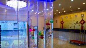 A hotel lobby with a large decorative water feature and a reception desk. - Wuduria Hotel (Nairobi)