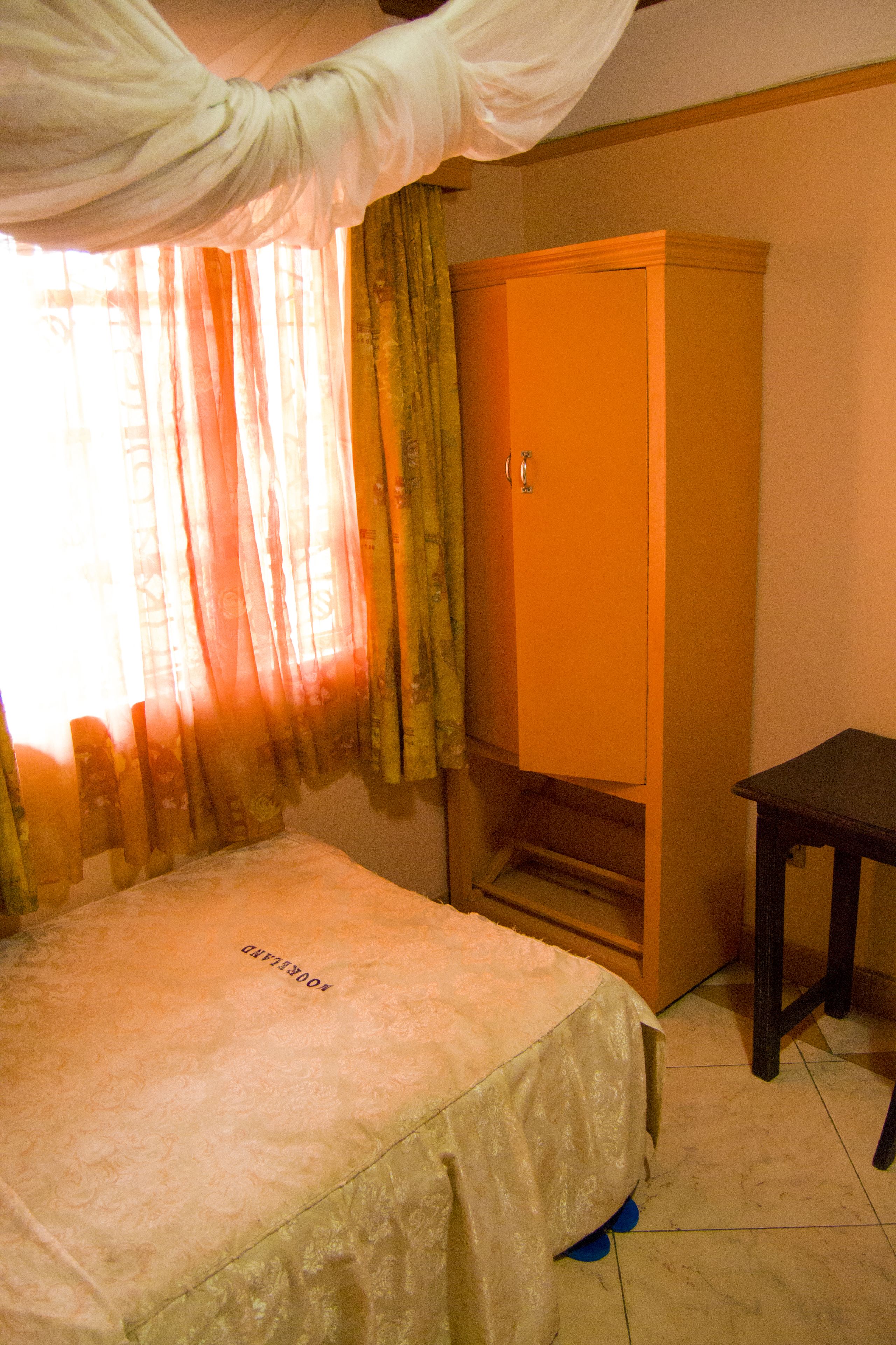 A room with a bed, a wardrobe, and a small table.