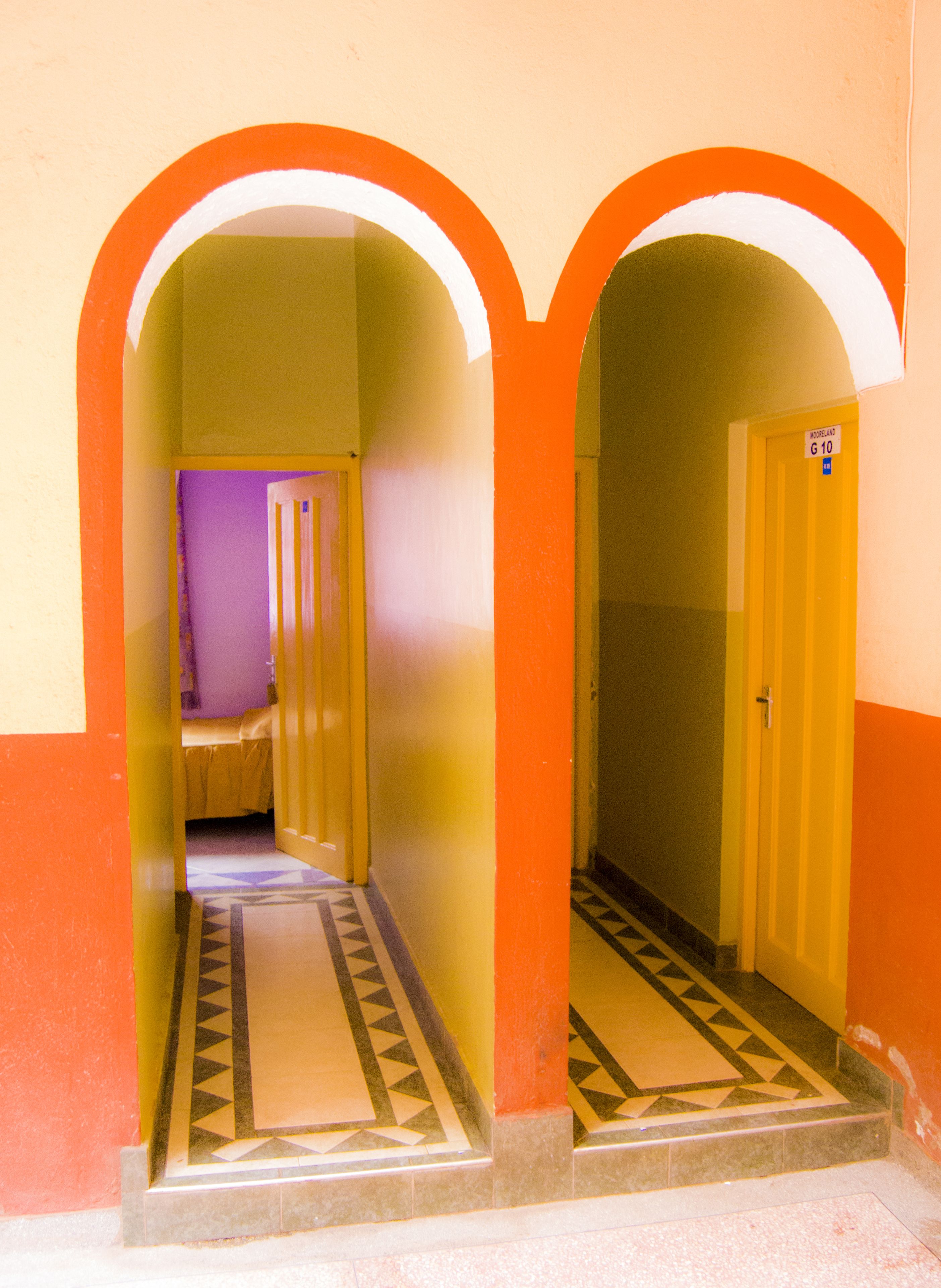 A hallway with two archways, a patterned floor, and a door with a sign.