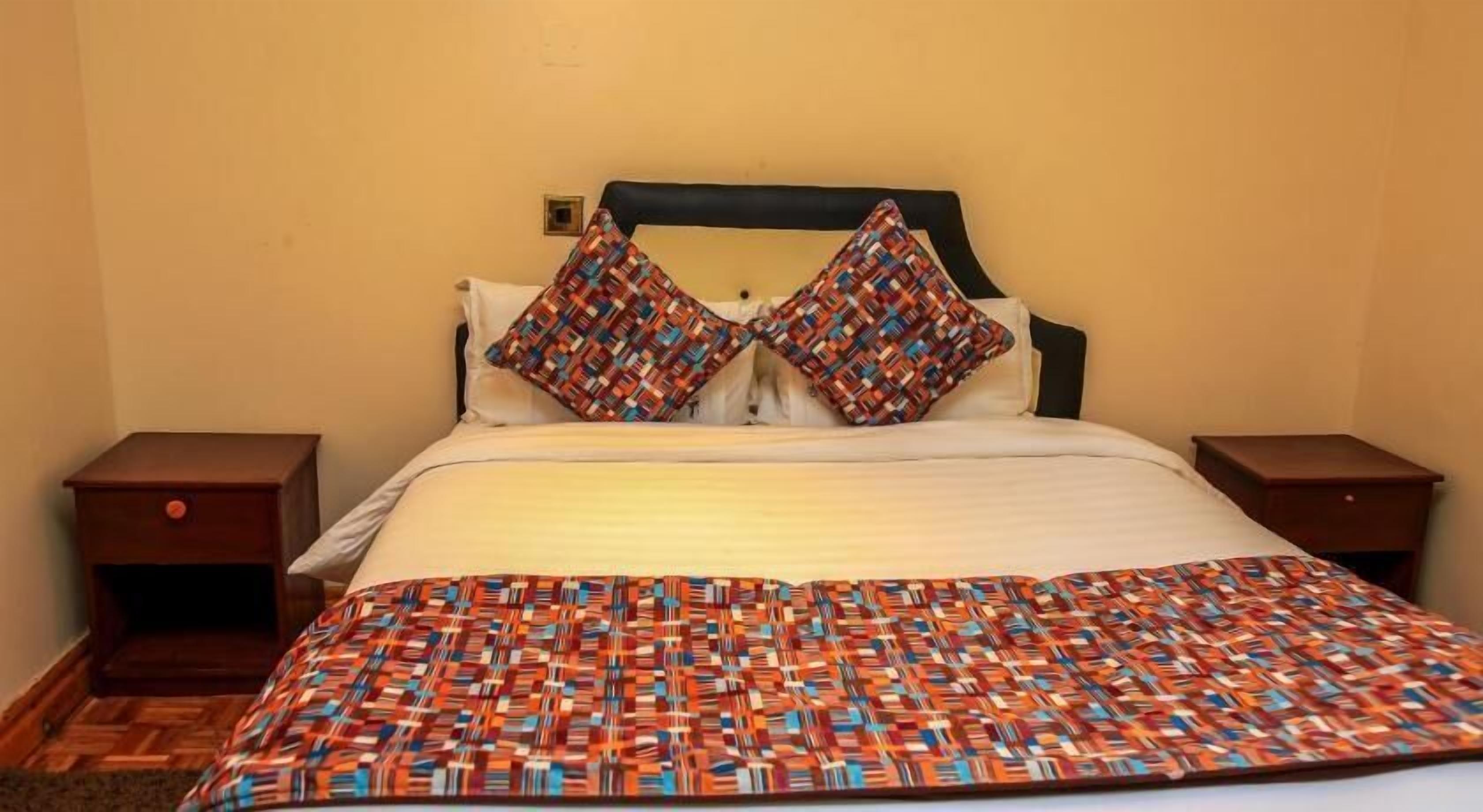 A bed with a patterned blanket, two pillows, and a headboard.