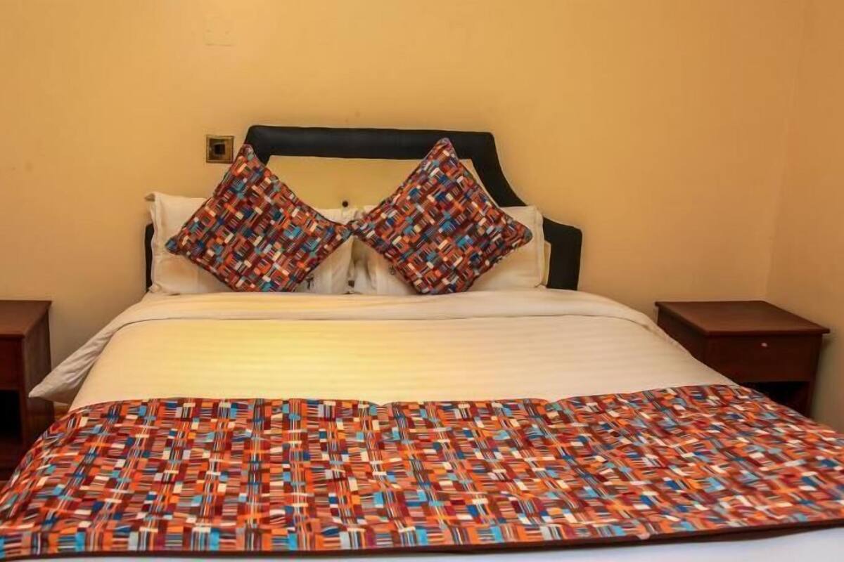 A bed with a patterned blanket, two pillows, and a headboard.