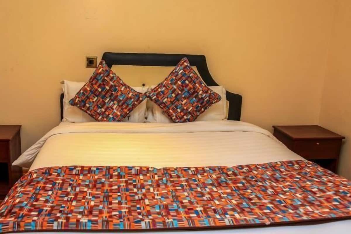 A bed with a patterned blanket, two pillows, and a headboard.