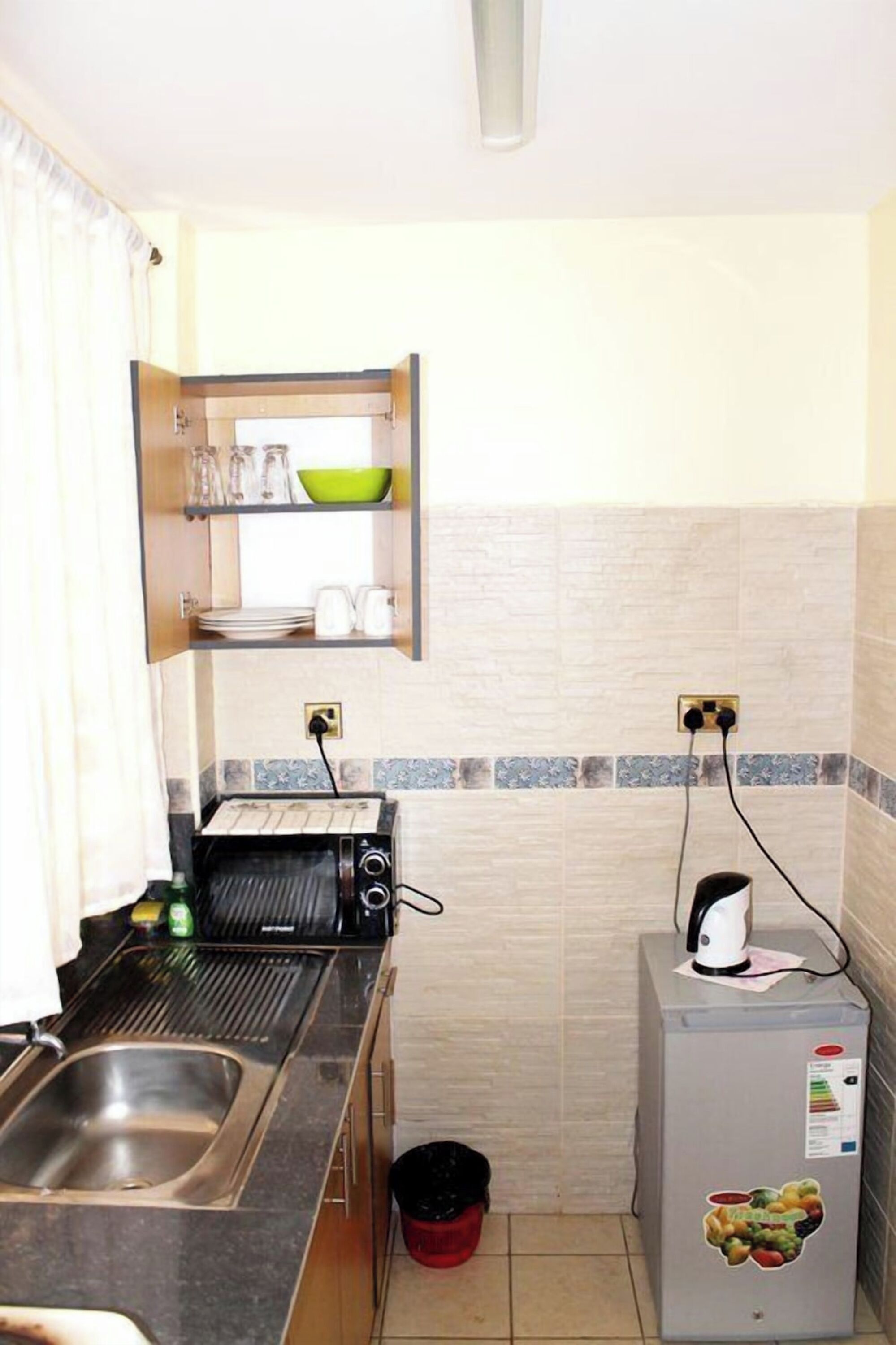 A compact kitchen with a built-in toaster, a small refrigerator, and a sink.