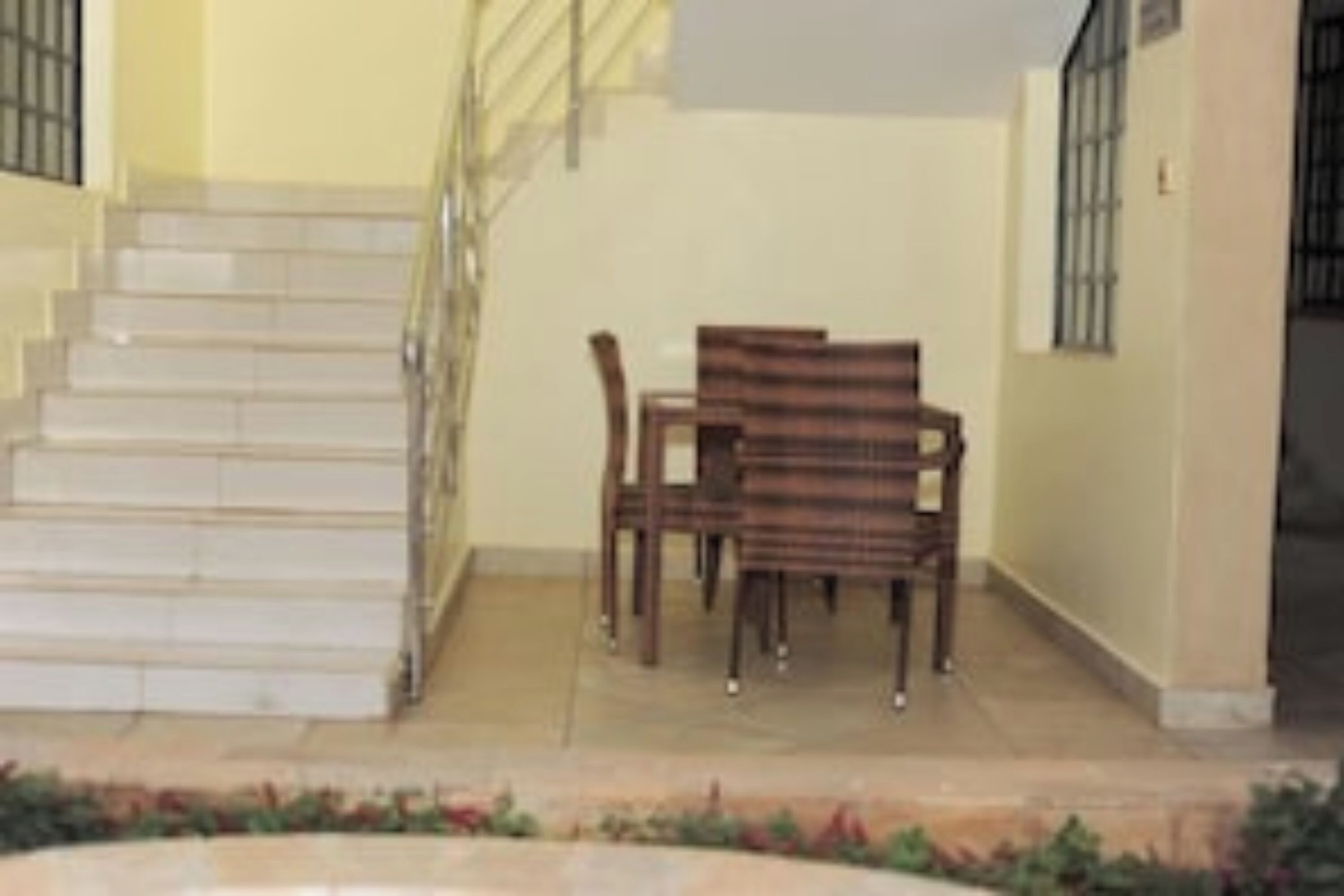 A staircase leading to an upper floor, a wooden bench, and a small table with chairs.