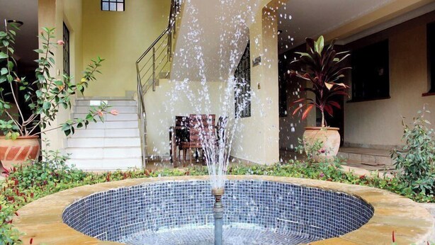 A circular water feature with a fountain in the center, surrounded by a tiled pool. - Davis Court Nyeri (Nyeri)