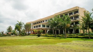 A multi-story hotel with a flat roof, surrounded by well-maintained lawns and palm trees. - Lake View Resort Hotel (Mbarara)