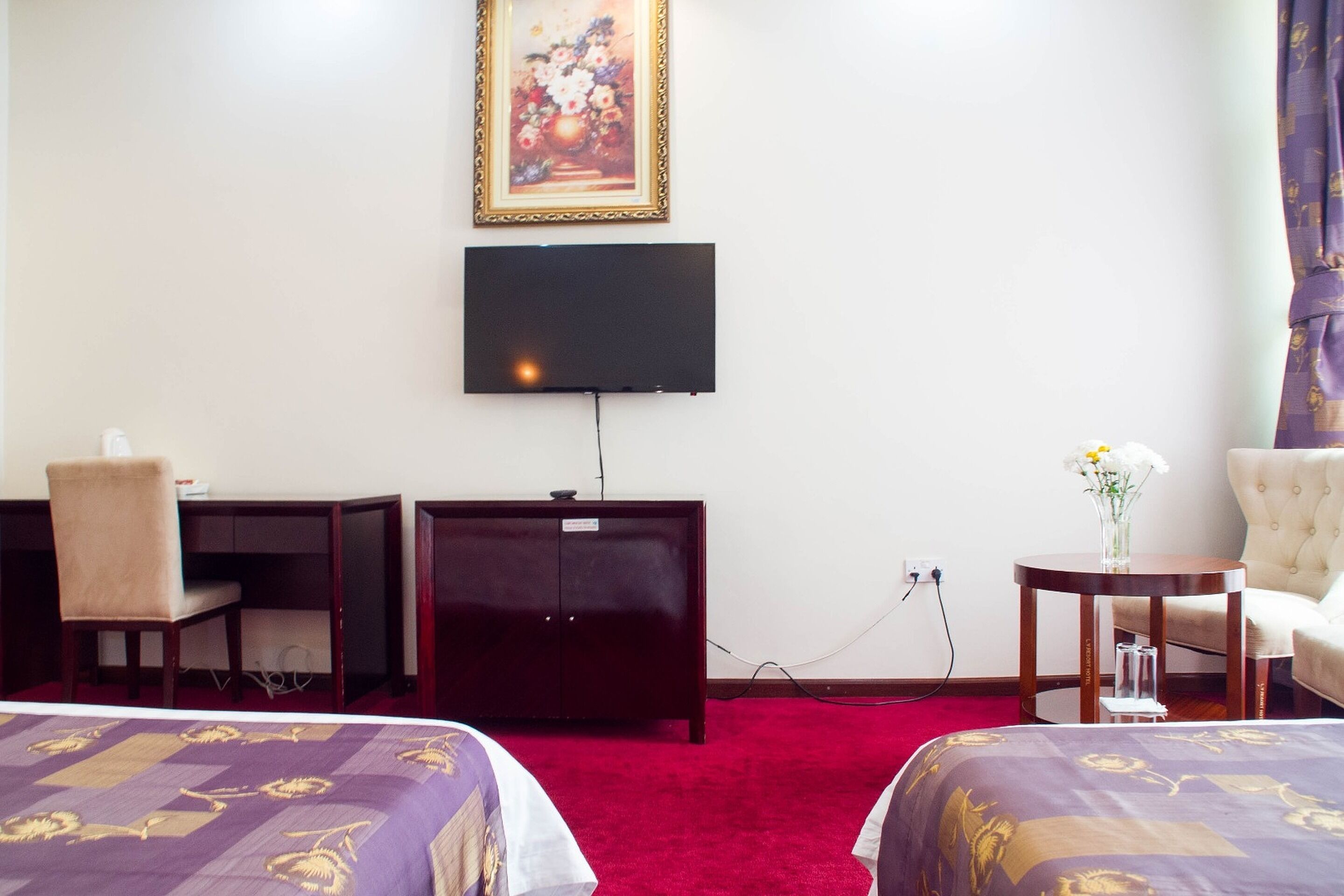 Une chambre d’hôtel avec deux lits, un bureau, une télévision et une chaise.