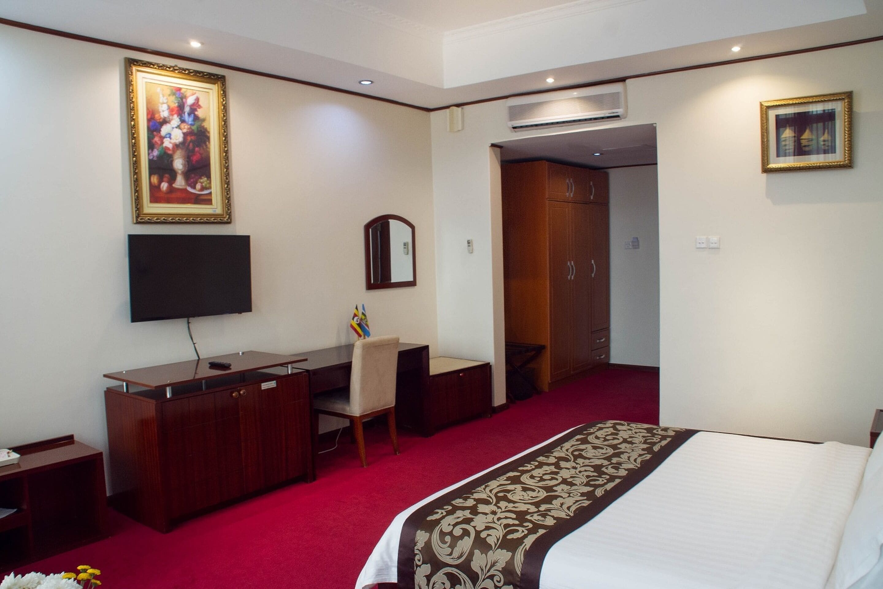 A hotel room with a bed, a desk, a chair, a television, and a wardrobe.