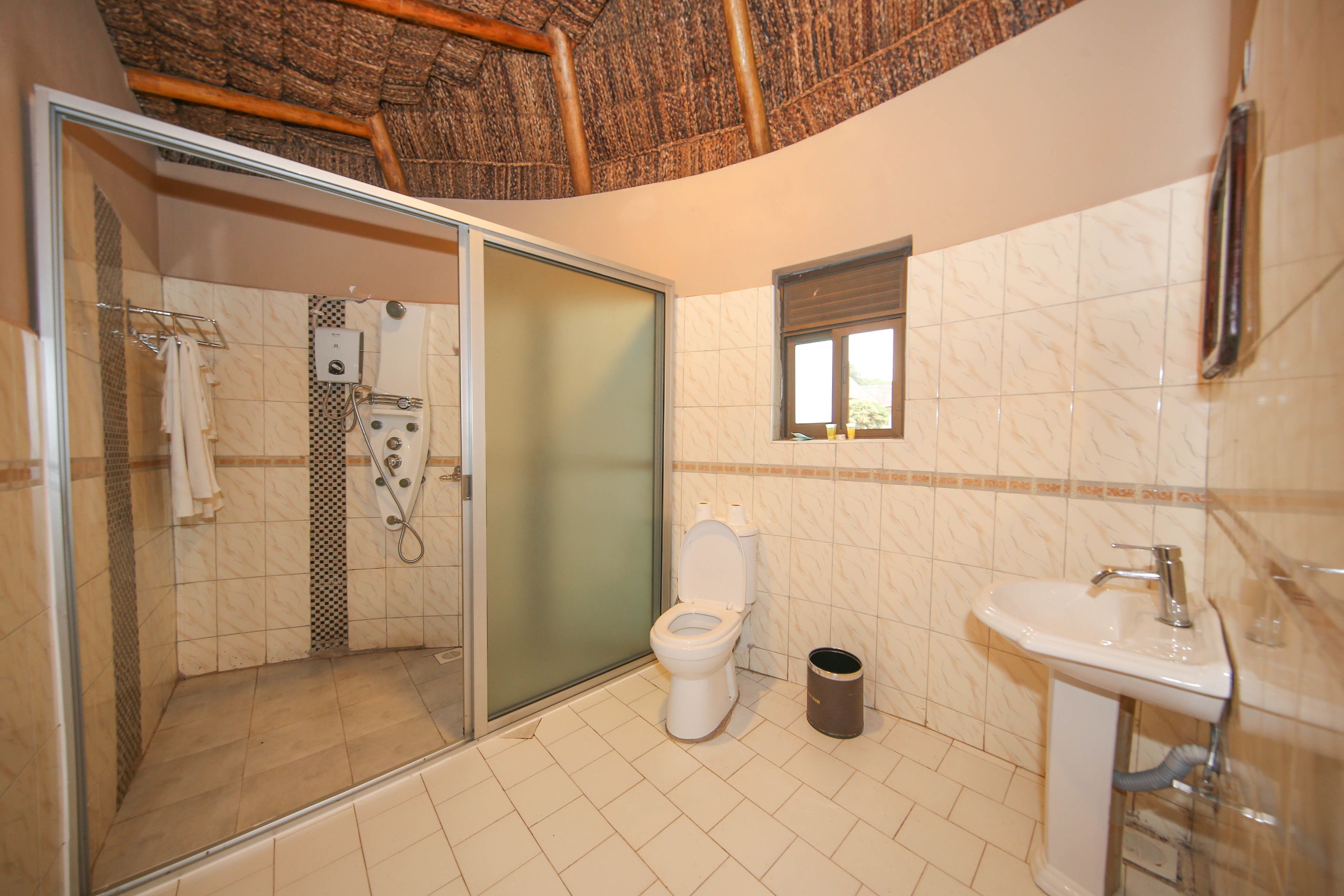 Ein Badezimmer mit Duschkabine, Toilette, Waschbecken und kleinem Fenster.