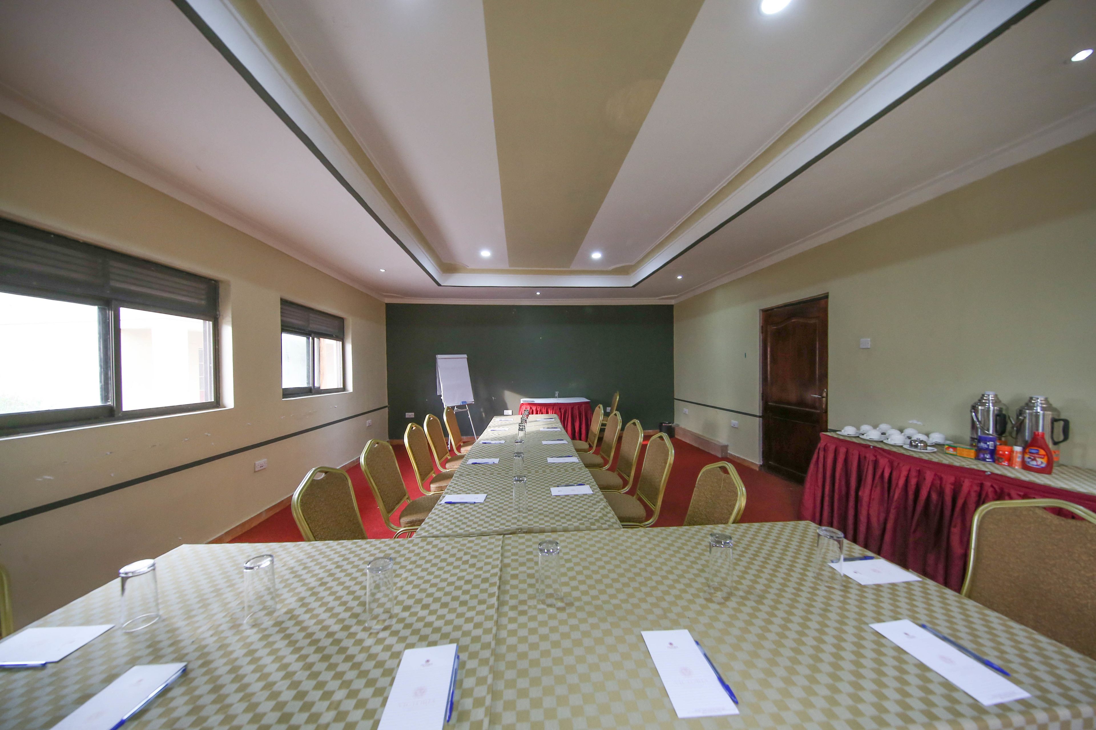 A conference room with a long table, chairs, a whiteboard, and a red tablecloth.