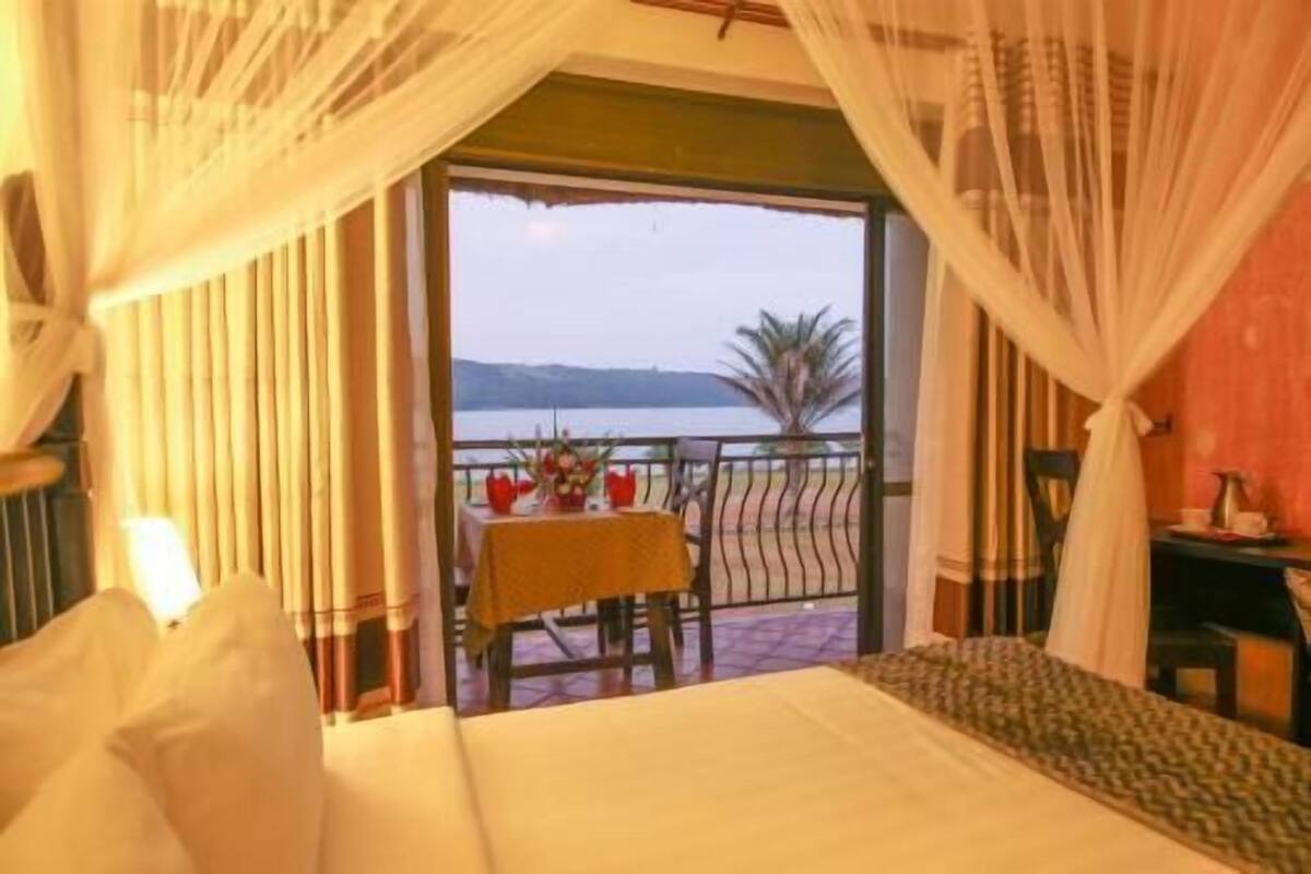 Una habitación con una cama, una mesa con un florero y vistas al mar.