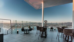 A rooftop terrace with a panoramic city view, furnished with tables and chairs, and a glass railing. - Hilton Garden Inn Silao Aeropuerto Bajio (Silao)