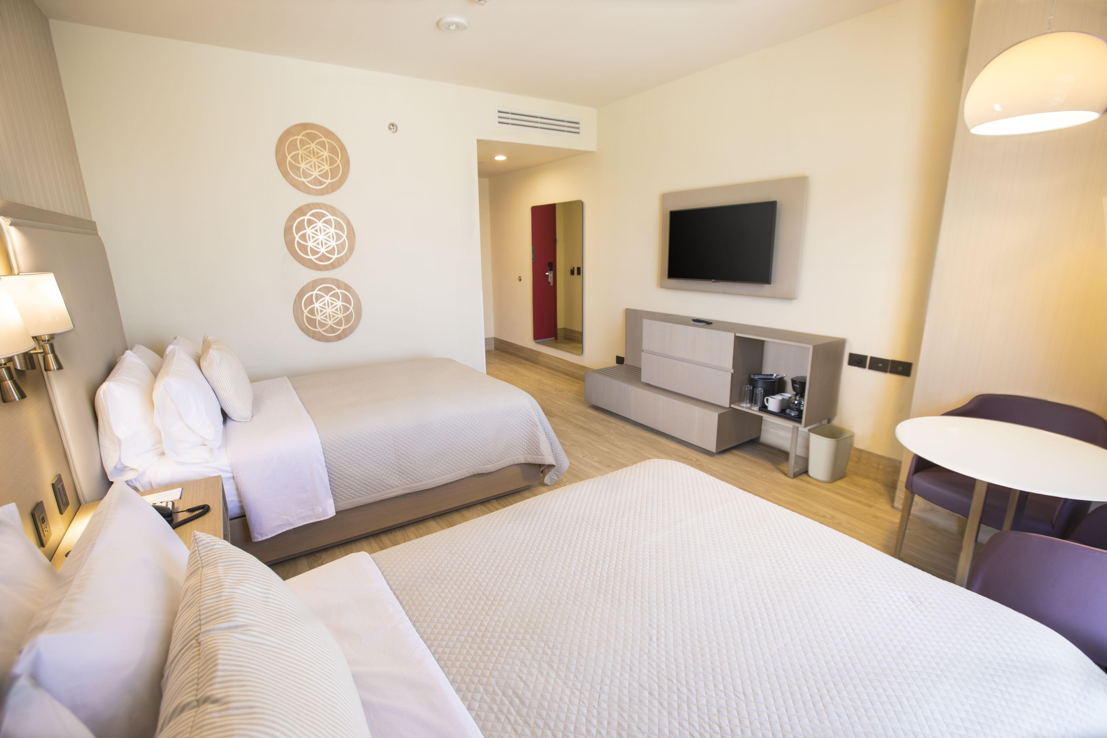 Habitación de hotel con dos camas, televisión, escritorio con silla y una mesita.