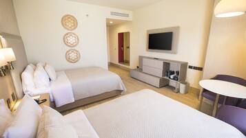 Habitación de hotel con dos camas, televisión, escritorio con silla y una mesita.
