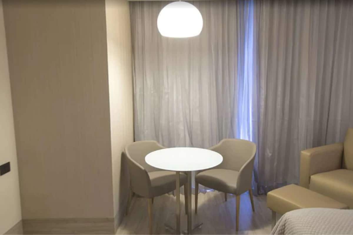 Una habitación de hotel con una mesa redonda, dos sillas, un sofá y una cama.