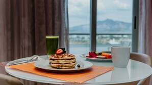 A breakfast table with pancakes, a green drink, and a fruit plate. - Hilton Garden Inn Silao Aeropuerto Bajio (Silao)