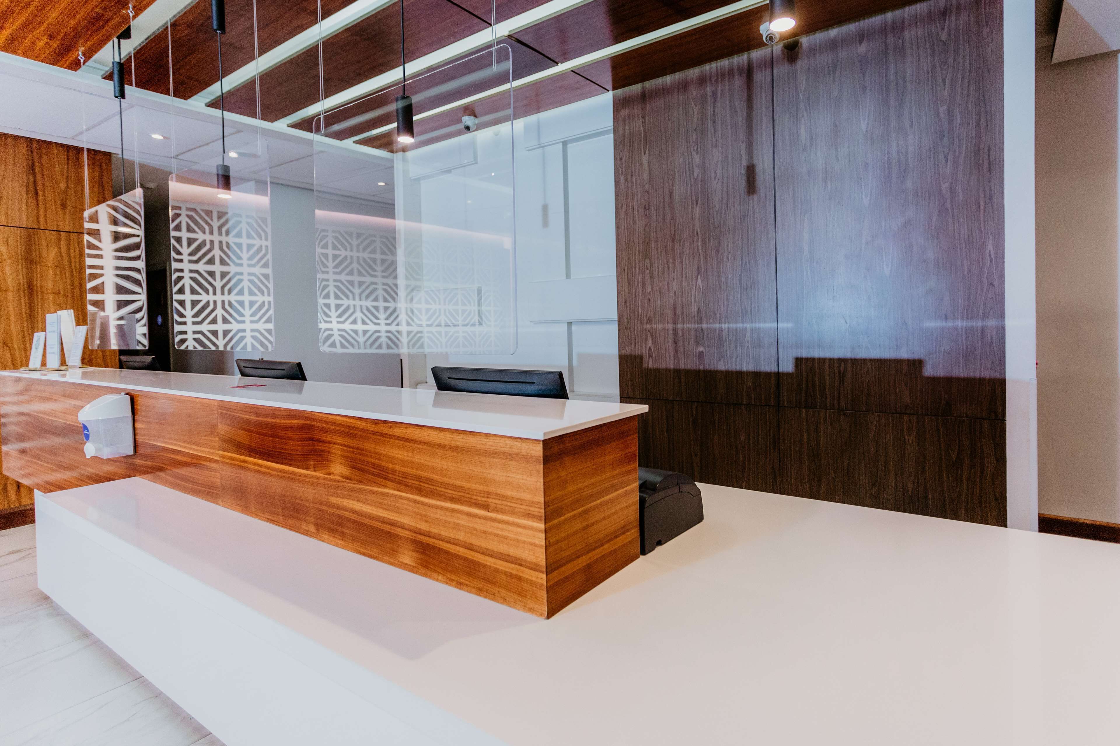 A modern reception desk with a wooden finish and a white countertop.