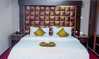A hotel room with a large bed, a padded headboard, two bedside tables, and a red carpet.