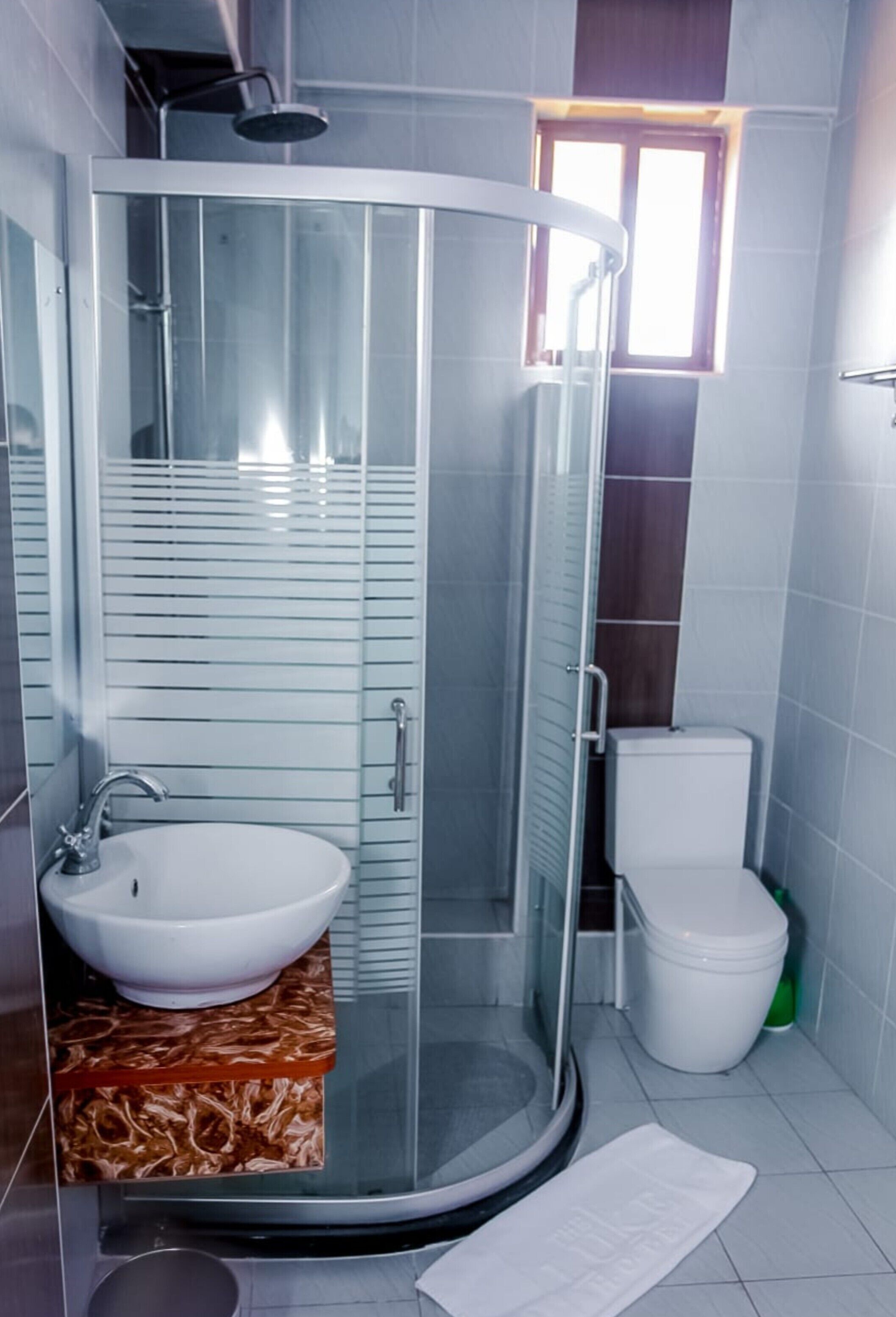 A bathroom with a glass-enclosed shower, a sink, and a toilet.