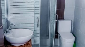 A bathroom with a glass-enclosed shower, a sink, and a toilet.