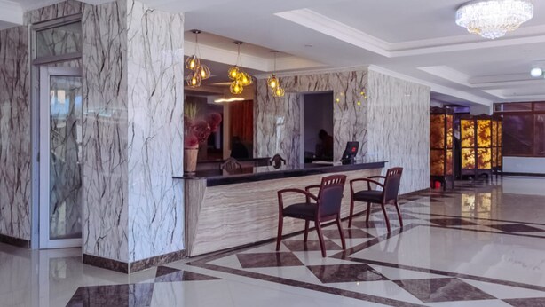 A lobby with marble walls, a reception desk, and a chandelier.