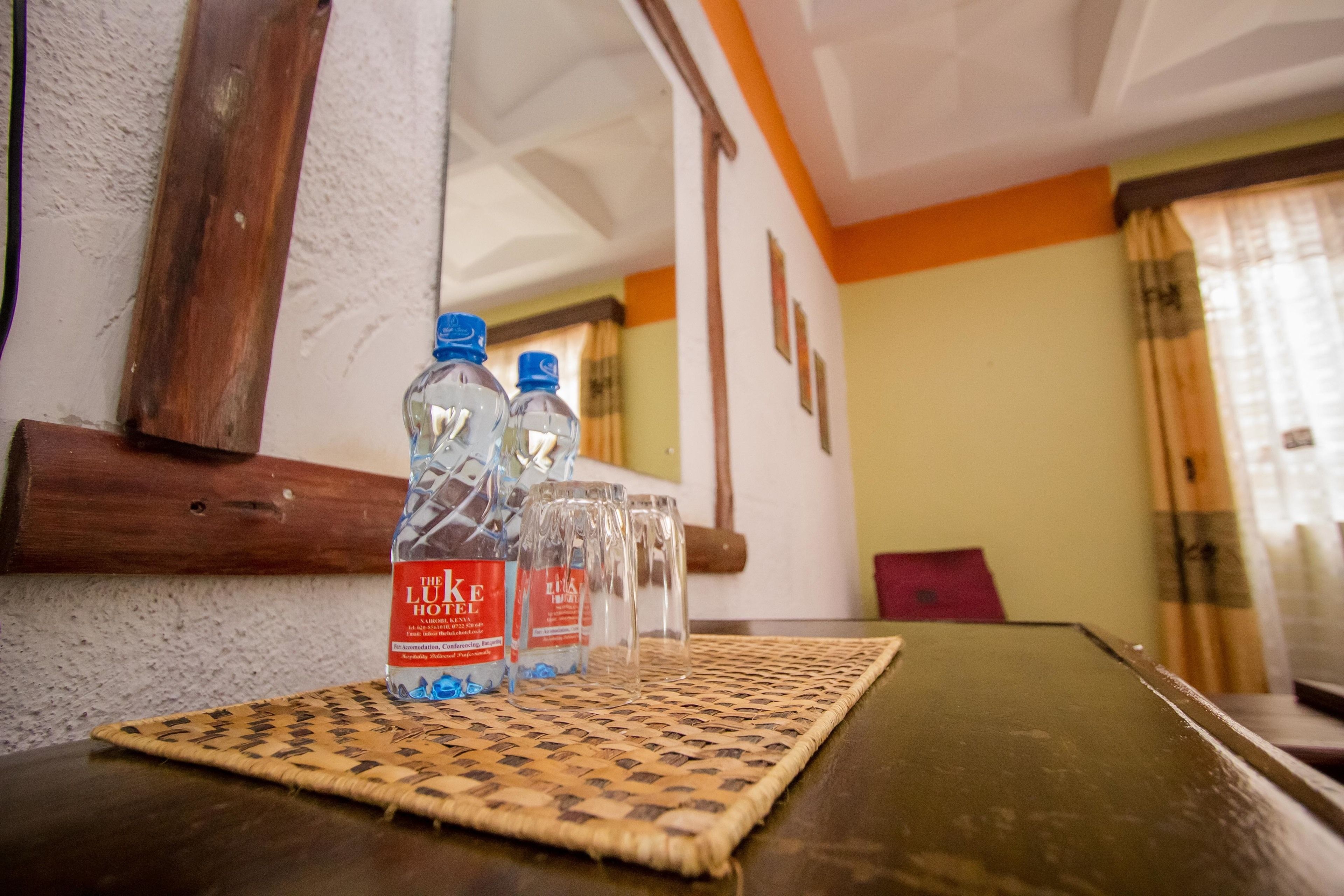 Una mesa con dos botellas de agua y tres vasos sobre un camino de mesa tejido.