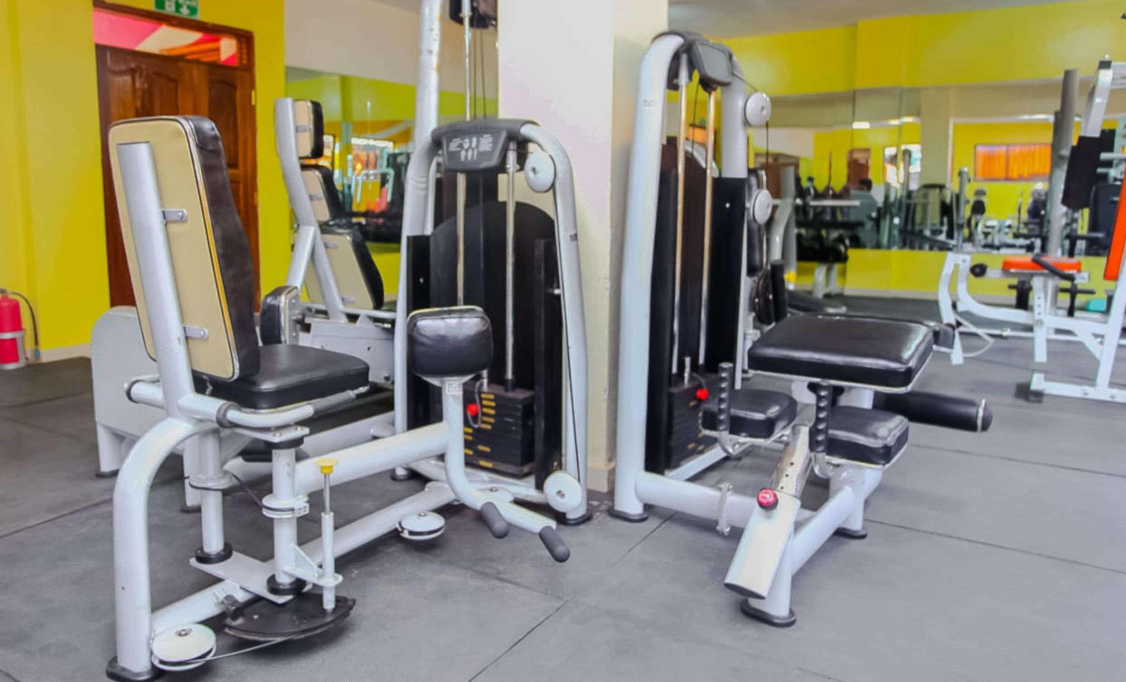Un gimnasio con diversas máquinas de ejercicio, incluyendo una prensa de piernas y una prensa de pecho.