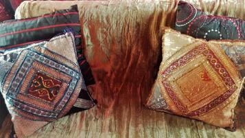 A room with a wooden floor, a red curtain, and a sofa with patterned cushions.