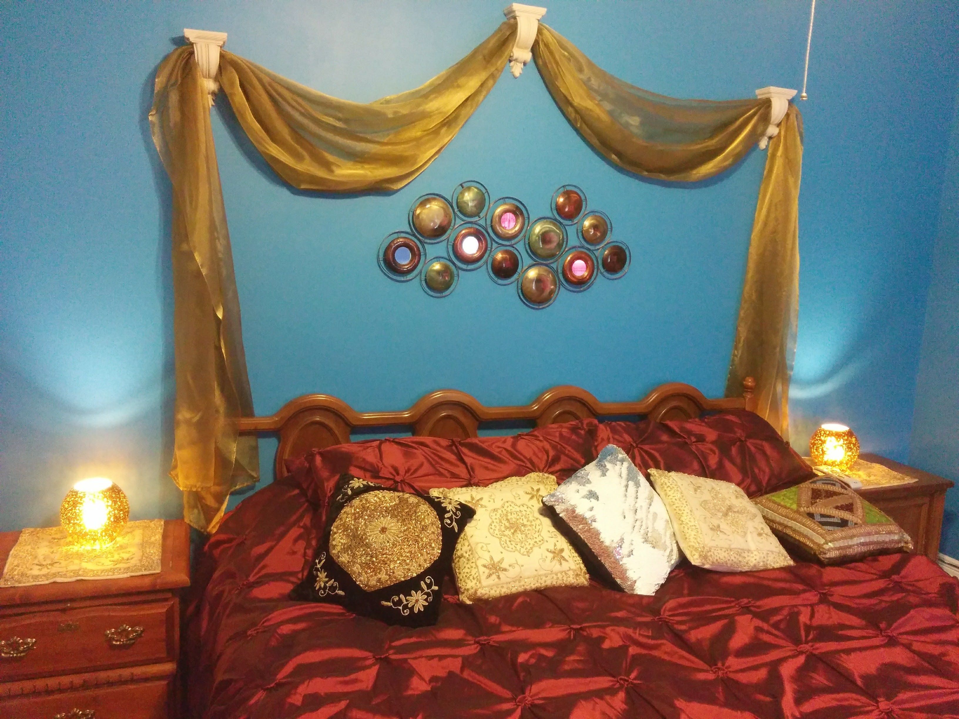 A bed with red bedding, a wooden headboard, and decorative pillows.