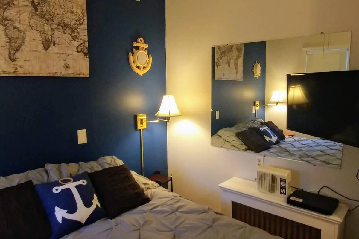 Une chambre d’hôtel avec un lit, un bureau doté d’une lampe, une télévision et une carte accrochée au mur.