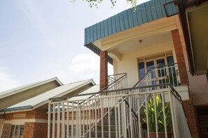 Un edificio con techo inclinado, balcón con barandilla de metal y fachada de ladrillo.