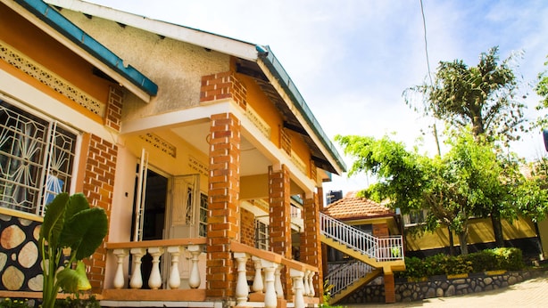 A two-story building with a balcony, stone steps, and a staircase leading to the upper floor. - Keba Inn (Entebbe)