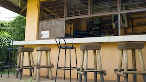 A bar with wooden stools and a yellow wall. - Keba Inn (Entebbe)