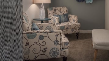 Una habitación con dos sillones tapizados, una mesita redonda y una lámpara de pared.