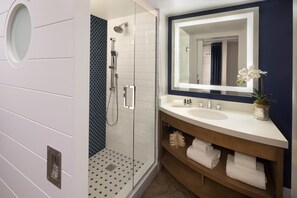 Ein modernes Badezimmer mit Glasdusche, großem Spiegel und Holzausstattung mit Handtüchern.