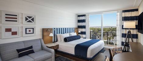 A hotel room with a bed, a sofa, a desk, and a balcony with a view.