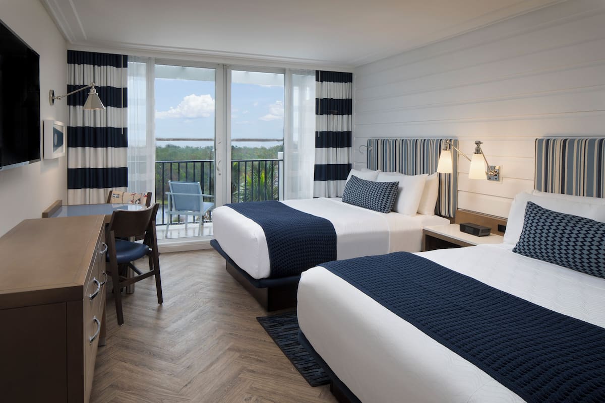 A hotel room with two beds, a desk, and a chair.