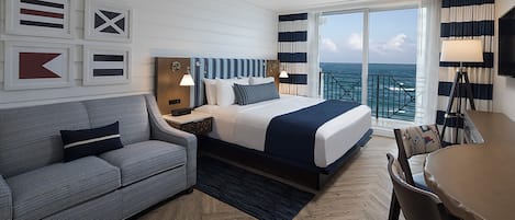 Une chambre d’hôtel avec un lit, un canapé, un bureau et une vue sur l’océan.
