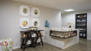 A modern interior with a marble reception desk, shelves with candles and toiletries, and a decorative wall with mirrors.