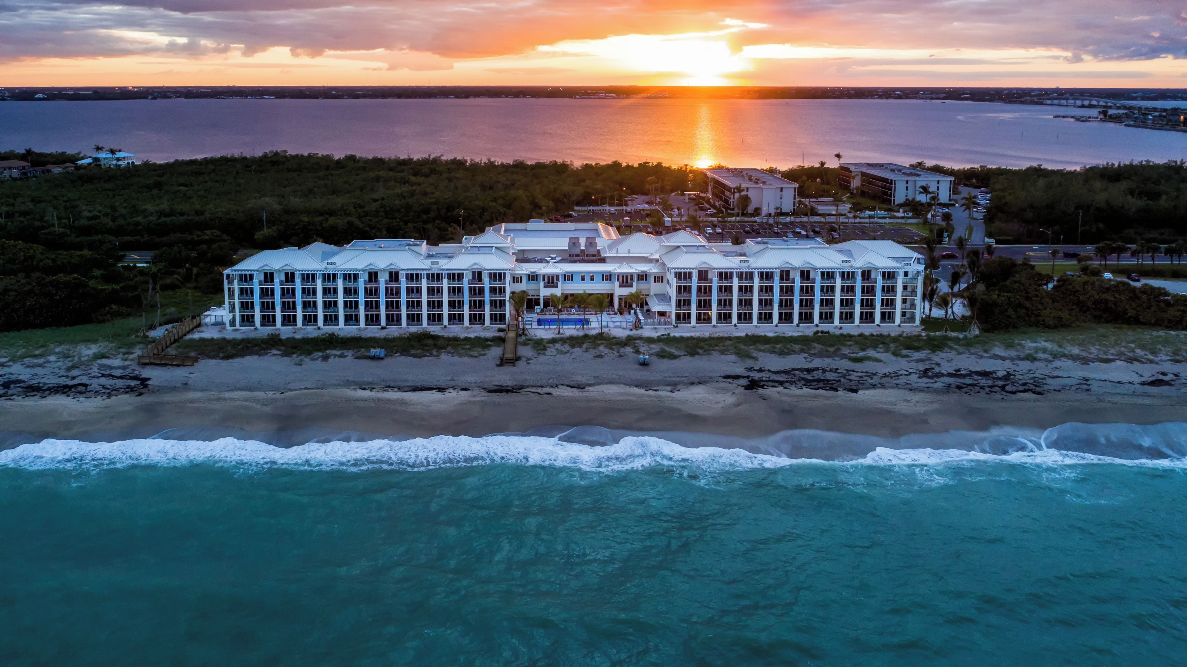 Ein Strandhotel mit mehreren Gebäuden, einem Pool und einem Strand im Vordergrund.