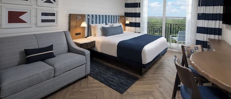 Ein Hotelzimmer mit Bett, einer Couch, einem Esstisch und einem Balkon mit Blick.