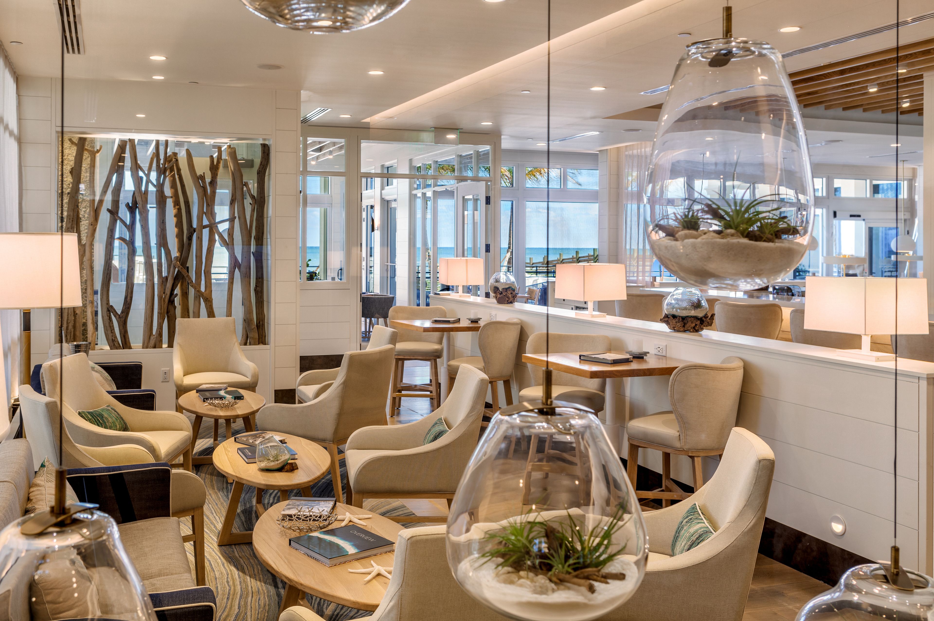 A modern lounge area with comfortable seating, glass walls, and decorative lighting fixtures.
