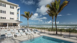 A poolside area with lounge chairs, a pool, and a view of the ocean. - Hutchinson Shores Resort & Spa (Jensen Beach)