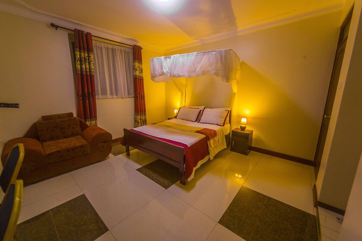 A bedroom with a bed, bedside tables, a chair, and curtains.