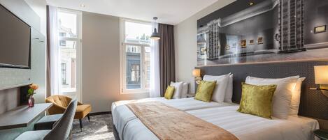 Ein Hotelzimmer mit einem großen Bett, einem Schreibtisch, einem Stuhl und Blick auf die Stadt.