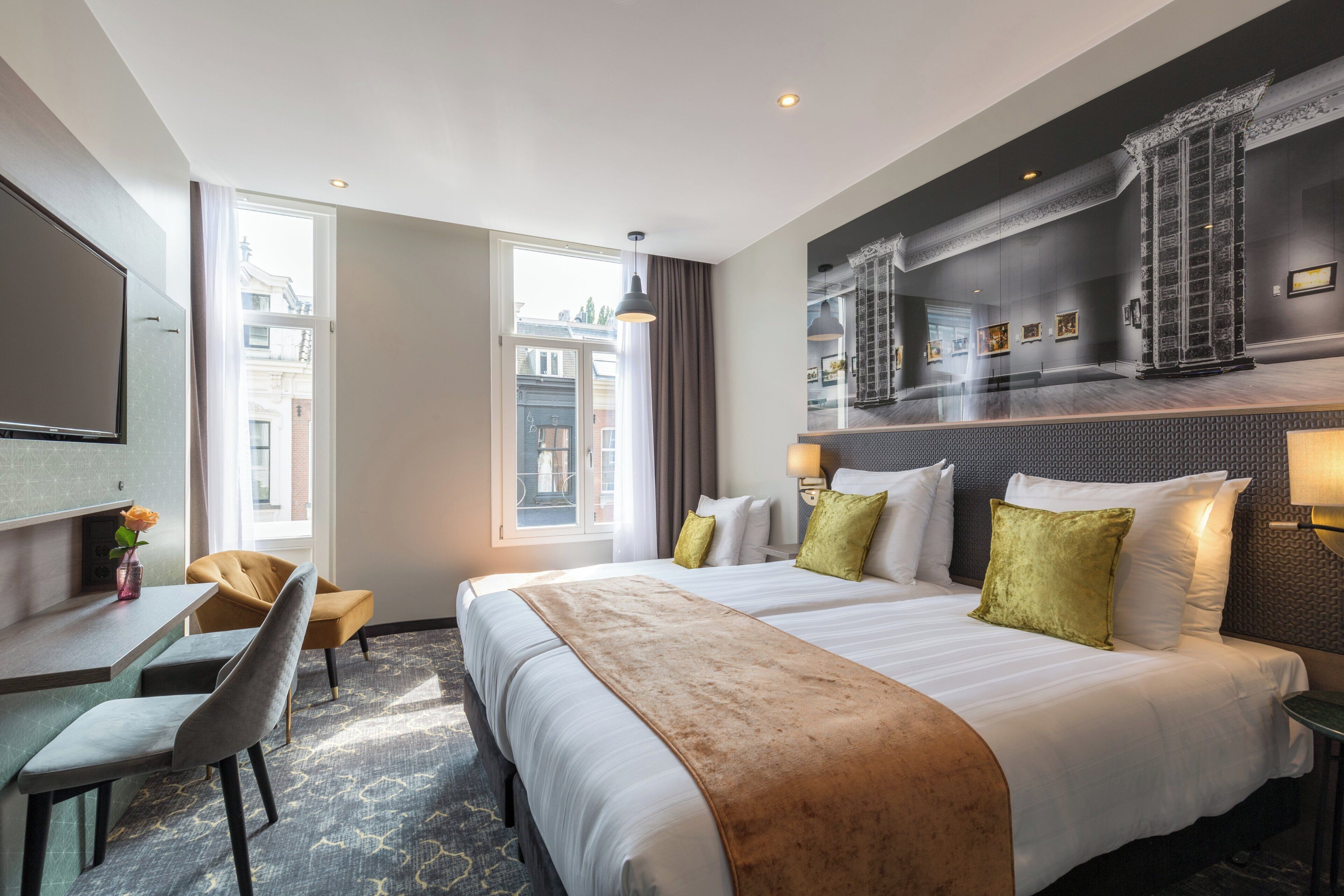 Une chambre d’hôtel avec un grand lit, un bureau, une chaise et une vue sur la ville.