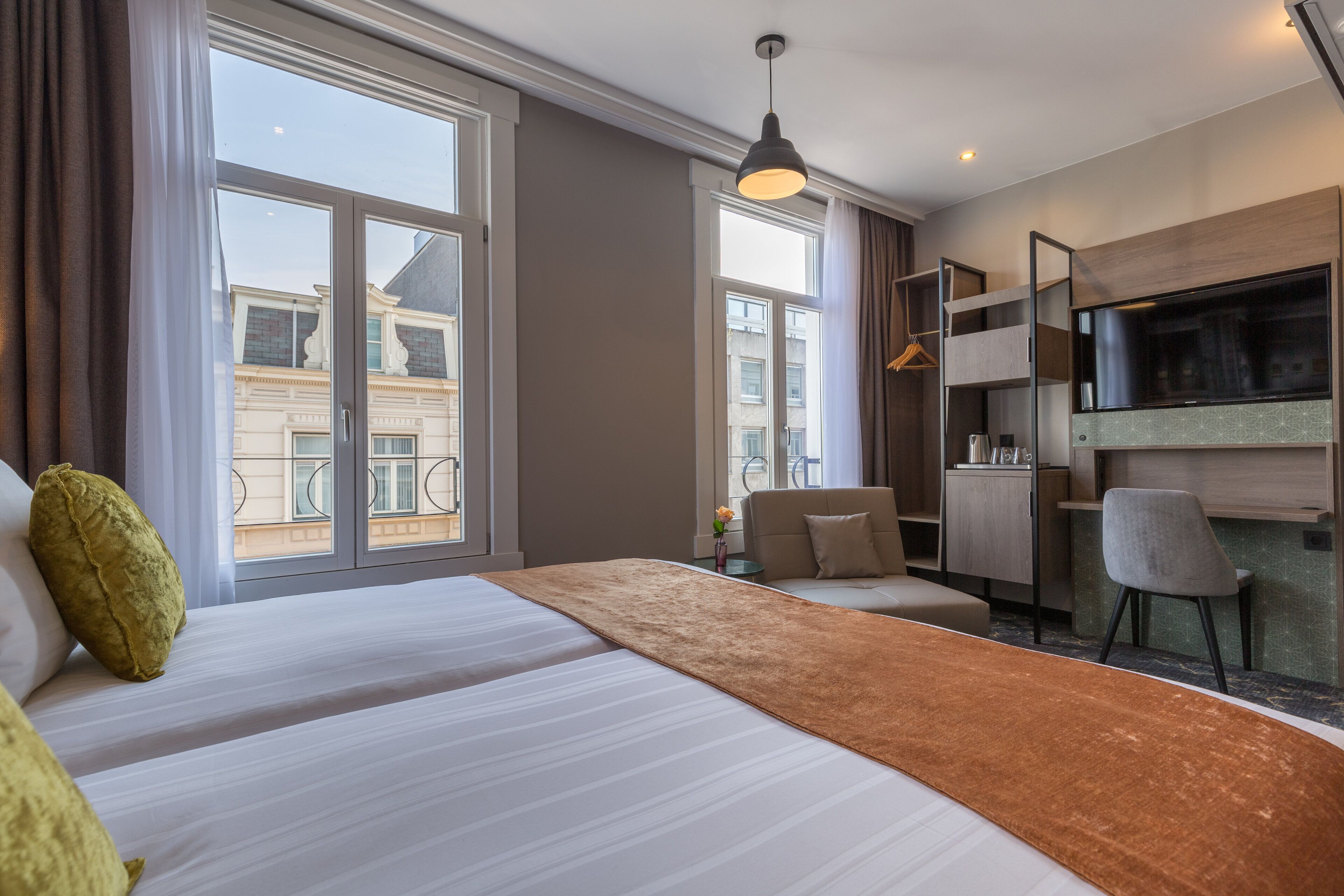 A modern hotel room with a large bed, a desk, and a TV.