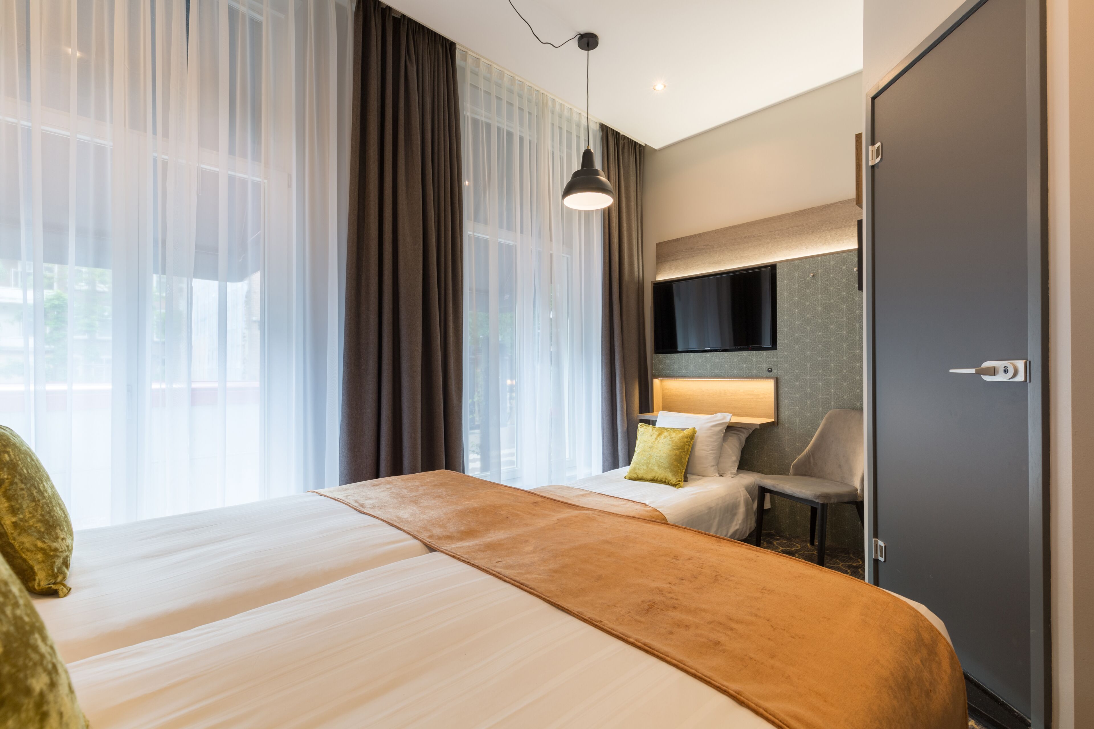 Een hotelkamer met een bed, een bureau, een stoel, een televisie en een kledingkast.